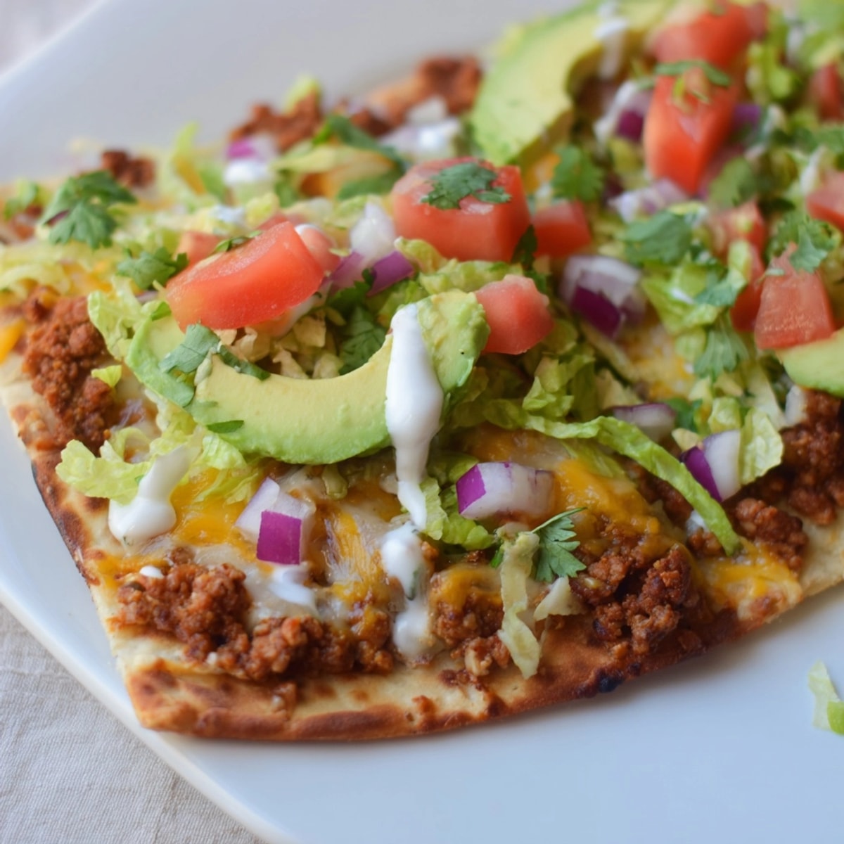 Overhead shot of a Spicy Turkey Taco Flatbread, garnished with creamy sour cream.