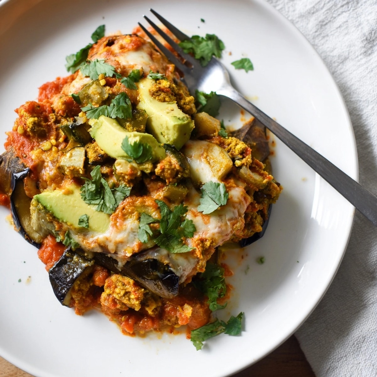 Golden Avocado Eggplant Curry Bake, bubbling cheese on roasted vegetables, ready to serve.