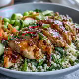 Freshly baked chicken slices and vibrant vegetables sit atop a bed of fluffy couscous tossed in a glossy sesame ginger dressing in these Sesame Ginger Chicken Couscous Bowls.