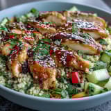 Bright red bell peppers, diced cucumbers, and shredded carrots add crisp texture to these colorful Sesame Ginger Chicken Couscous Bowls.