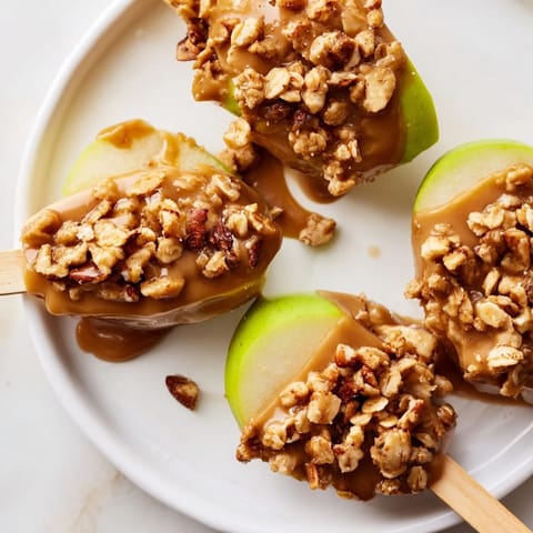 Crunchy caramel apple pops coated in granola, perfect for a festive snack.  