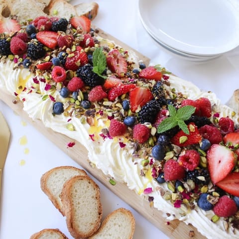 Vibrant butter board dessert topped with berries, nuts, and chocolate shavings.  