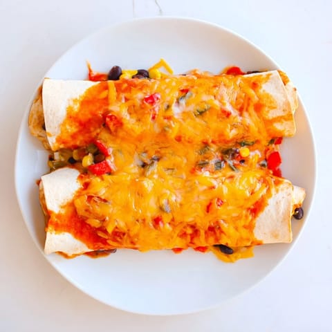 Warm and cheesy Farmers Market Vegetarian Enchiladas, baked in a rich red sauce, garnished with fresh cilantro.