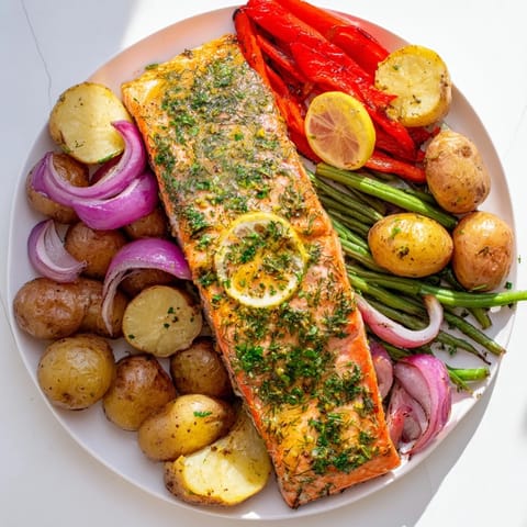 Vibrant sheet pan of Lemon Herb Salmon & Potatoes, ready to serve with fresh lemon wedges.