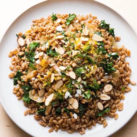 This image shows a beautifully plated Warm Farro & Greens Pilaf, garnished with toasty almonds.