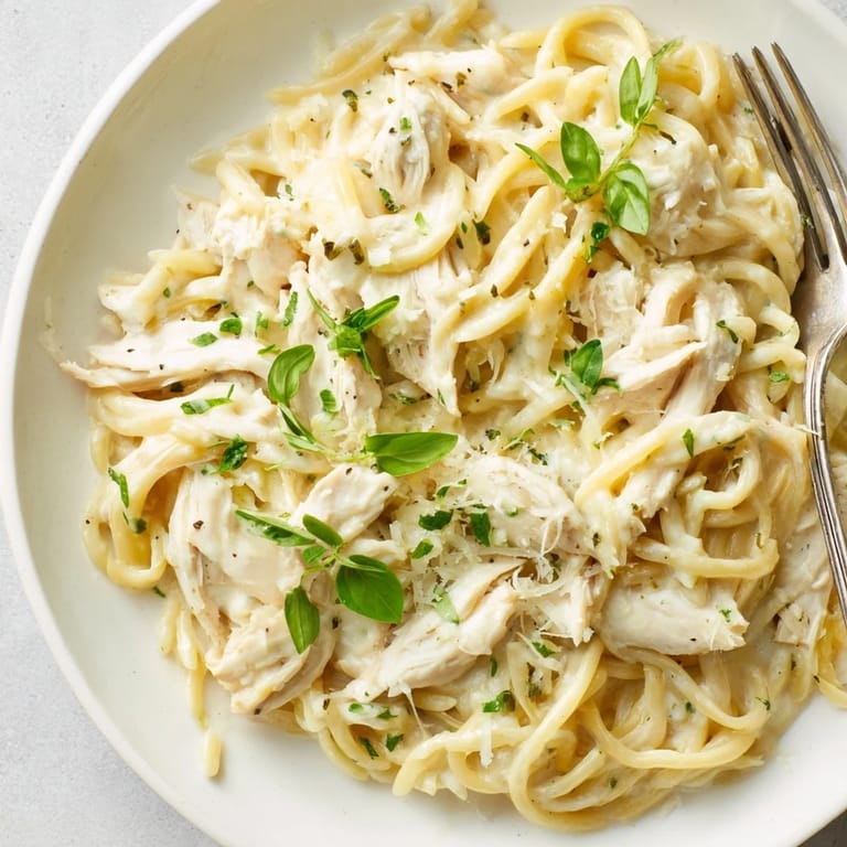 A comforting plate of Creamy Lemon Herb Chicken Orzo topped with fresh basil and cheese.  